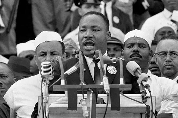Martin Luther King Jr. hält eine Rede an einem Podium voller Mikrofone